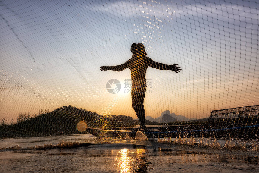 亚洲渔民在日落时在湖边的木船上投掷渔网农村渔民生活方式的概念华富里图片
