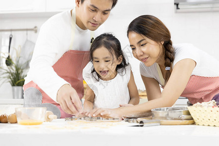 快乐的亚洲家庭父亲母亲和女儿正在家里的厨房里准备面团图片
