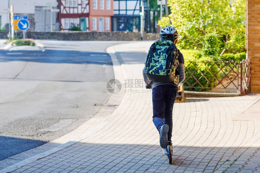 快乐的小孩男戴着眼镜和背包或滑板车上的书包上学路上的小学生户外健康可爱的孩子从电晕大流行病隔图片