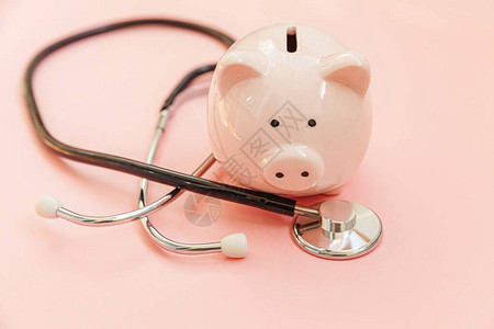 医学生设备听诊器和储钱罐隔离在粉红色柔和的背景医疗保健财务检查或节省医疗保险费用概背景图片