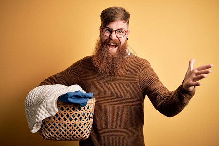红发爱尔兰红头发男子留胡子在黄色背景下洗家务衣物图片