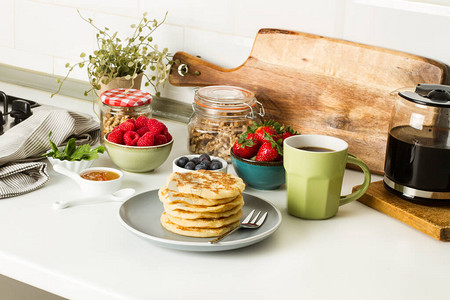 煎饼加浆果和蜂蜜在灰色盘子上厨房柜台图片