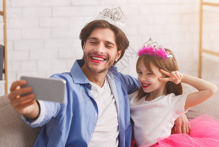 快乐的父亲和女儿身穿公主装扮在家里自拍图片