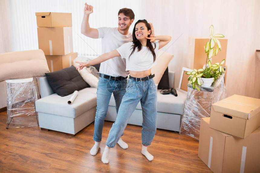 喜出望外的年轻夫妇在纸箱附近的客厅里跳舞娱乐图片