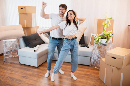 喜出望外的年轻夫妇在纸箱附近的客厅里跳舞娱乐图片