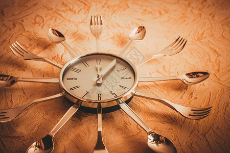 墙上的时钟显示正午表盘饰有餐具正确的饮食图片