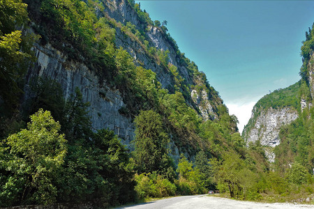 阿布哈兹风景如画的峡谷这条路穿过陡峭的岩石峭壁山坡上长满了鲜绿色的植物夏日阳背景图片