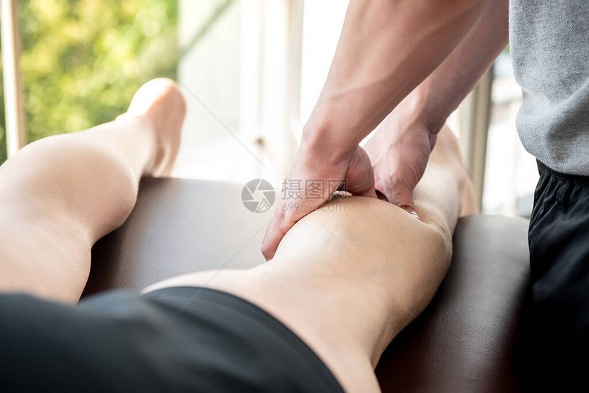 男治疗师在诊所为床上的病人提供腿部和图片