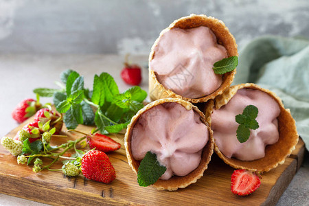 自制有机草莓冰淇淋草莓冰淇淋放在轻石或板桌上的华夫饼锥图片