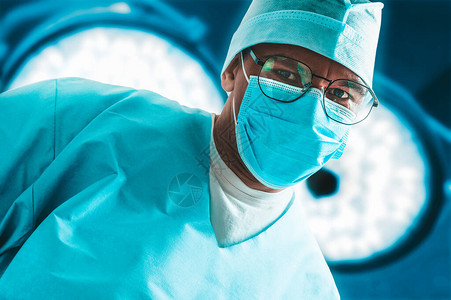 身戴外科灯具背景面罩的医生肖像医学概图片