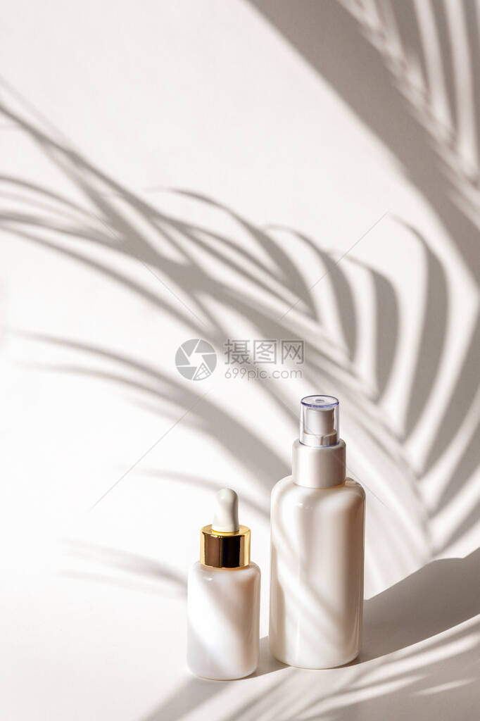 白色墙底的白板和棕榈叶阴影下的白包中的化妆品和血清自然皮肤图片