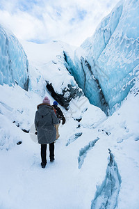 威廉王子声音两名徒步旅行者在阿拉斯加马塔努斯卡冰川的雪地上徒步他们正沿着一条小路进入冰洞寒假期间的极端冒险在背景