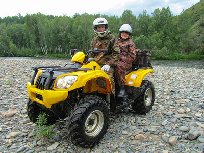 穿着迷彩服和摩托车头盔的快乐老年男女骑着黄色ATV图片