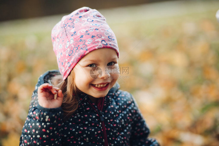 一个可爱的小女孩戴着粉色印花帽子和深色印花冬季夹克的股票照片图片