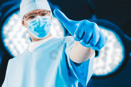 医生在外科灯具的背景之下展示了一只举起的手指医学概图片