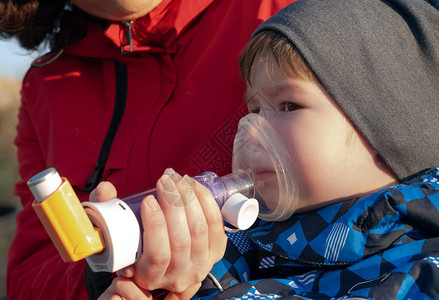 一名患有支气管哮喘病的小男孩在户外用气溶胶吸图片