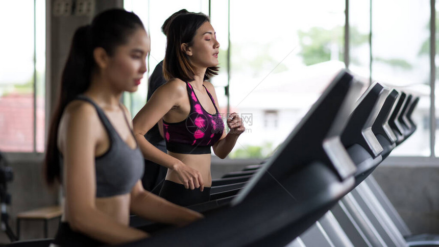 亚洲妇女和朋友在运动健身馆的跑步机上进行锻炼图片