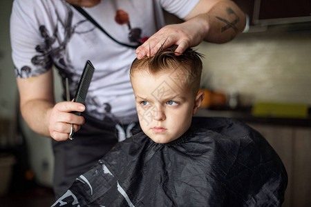 在家理发店和美发男士和儿童的发型理发师剪掉男孩适合孩子的时尚发型理发师用理发剪梳理背景图片