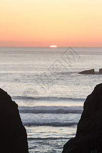 明亮的橙色太阳落到地平线后方给天空带来温暖的音调笼罩着俄勒冈州福岩公图片