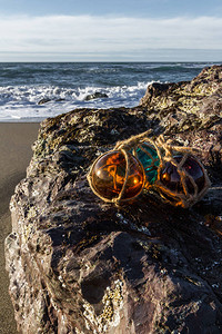 下午在俄勒冈海岸岩石上和沙滩上有多彩的玻璃漂浮在背图片