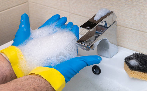 打扫浴室手拿着橡胶手套用洗涤剂清洗脸盆手图片