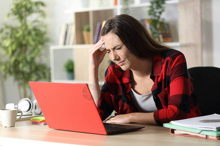有红色笔记本电脑痛苦头痛头痛的学生妇女坐在家图片