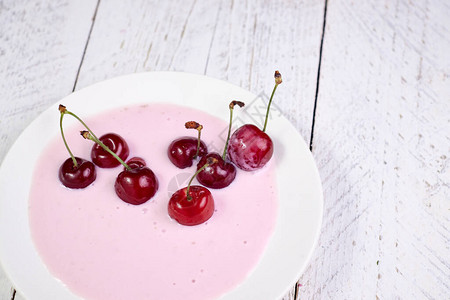 酸奶中的红樱桃白盘特写健康的早餐和图片
