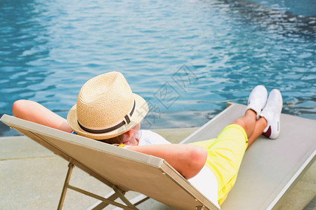 躺椅和游泳池男孩在游泳池附近的长椅上放松旅游概念旅游酒店业务休息图片
