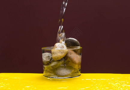透明玻璃杯里面有石块水喷洒和扔下水滴图片