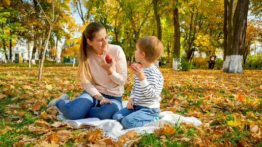 年轻微笑的母亲和小儿子的肖像在秋天公园图片