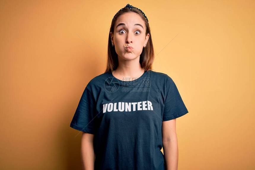 穿着志愿T恤的年轻美女在黄色背景下做义工图片