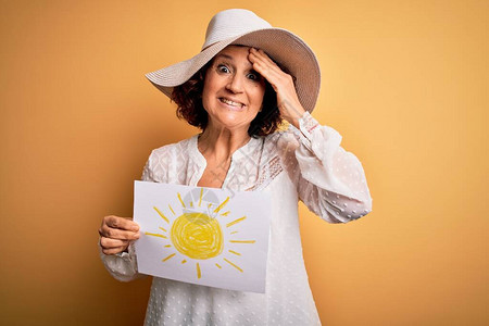 中年卷发女人在度假时拿着黄色背景上的太阳图像背景图片