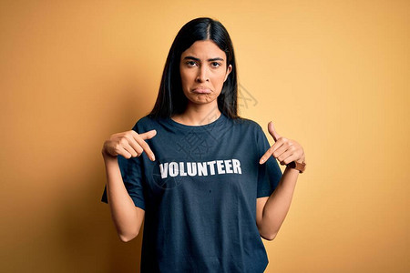 年轻漂亮的西班牙裔女穿着志愿者T恤作为社会慈善道德指向下方图片