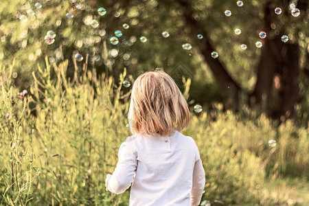 金发的小女孩在公园里抓住肥皂泡图片
