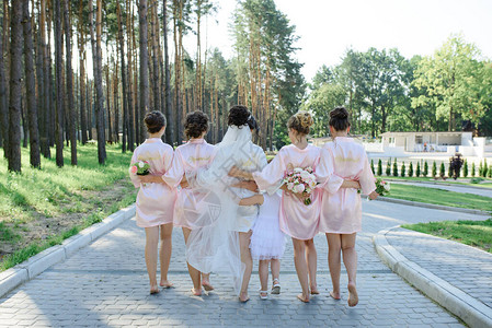 全长度的新娘正与伴娘一起站在一件白色大衣上图片