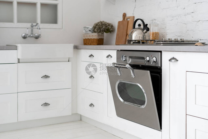 现代房屋的厨房内部配有白色家具燃气灶开放式烤箱木柜台面和窗图片