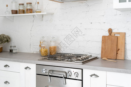 明亮现代风格的厨房内部概念白色家具新燃气灶烤箱木制橱柜和抽屉台面复印空间和墙背景图片
