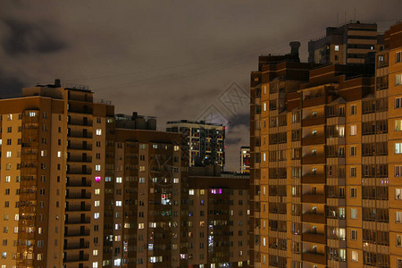 夜间在阴云的天空下照亮窗户的城市图片