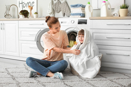 女人和她可爱的小女儿在家洗衣服图片