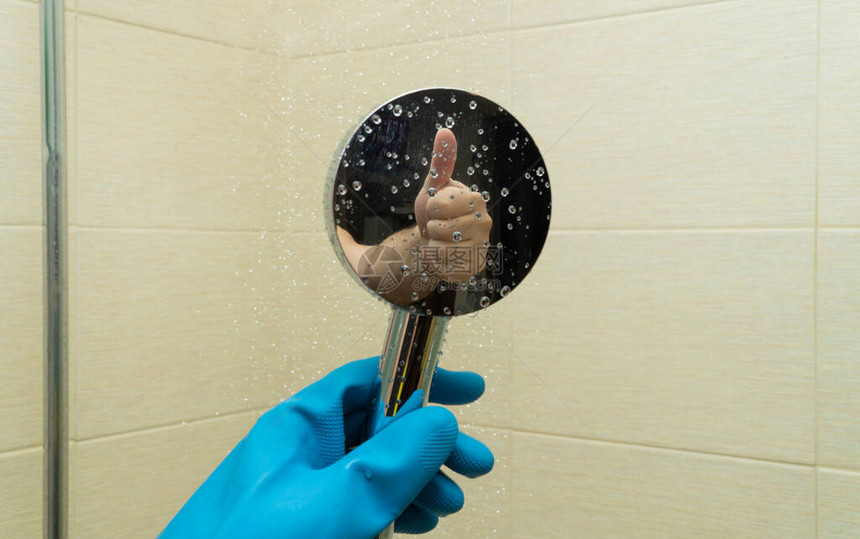 淋浴喷壶在手上戴着橡胶手套清洁浴室和清洁淋浴间一只手做出善意的姿态的倒影良好和高质量工作的概图片
