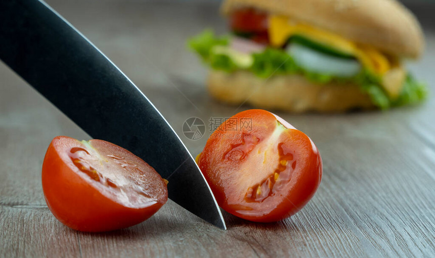 用尖利刀切番茄做三明治吃早餐美味汉堡在木质地表上洒满芝麻种子的鸡肉里快图片