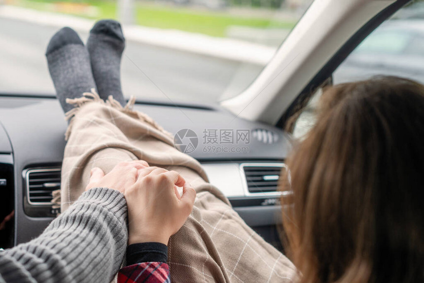 女人的脚穿着袜子包裹在汽车仪表板上的格子里男司机牵着一名在高速公路上行驶的女乘客的手情侣出图片