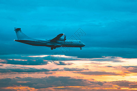 商用飞机在戏剧日落光线下在云层上空飞行图片
