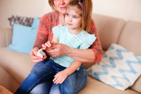 在家坐在沙发上用抗菌湿巾给小孙女消毒手背景图片