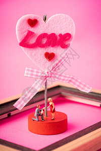 爱情观粉红色背景下的微型情侣背景图片