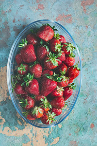 新鲜的成熟草莓在蓝色背景的玻璃碗图片