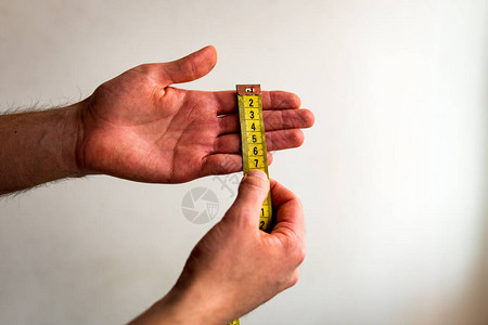 用黄色卷尺横向测量左手指从食指到小指的人白色背景图片