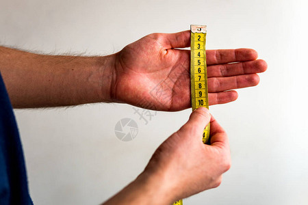 用黄色卷尺横向测量左手指从拇指到小指的人白色背景图片