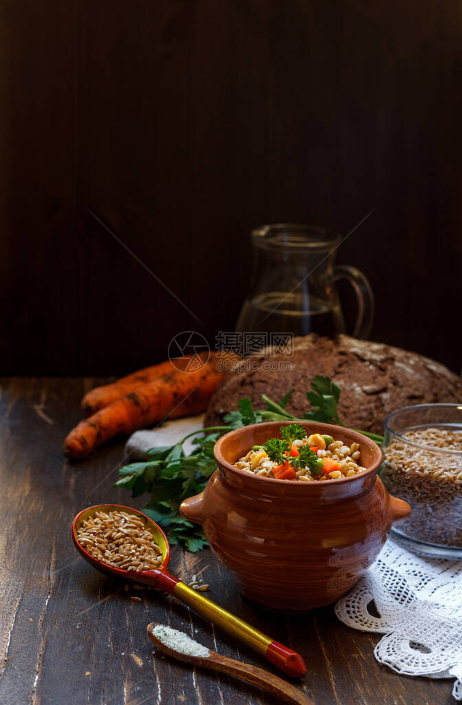 石块上加胡萝卜黑麦面包和木勺子的碗粥图片