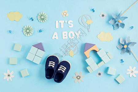 可爱的新生男婴鞋与节日装饰在蓝色背景婴儿送礼会生日邀图片